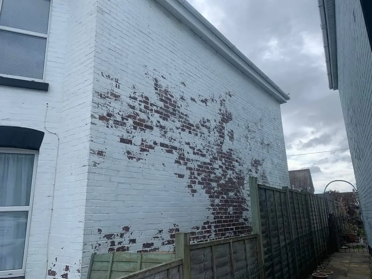 Peeling paint on a brick wall before redecoration in Sidmouth